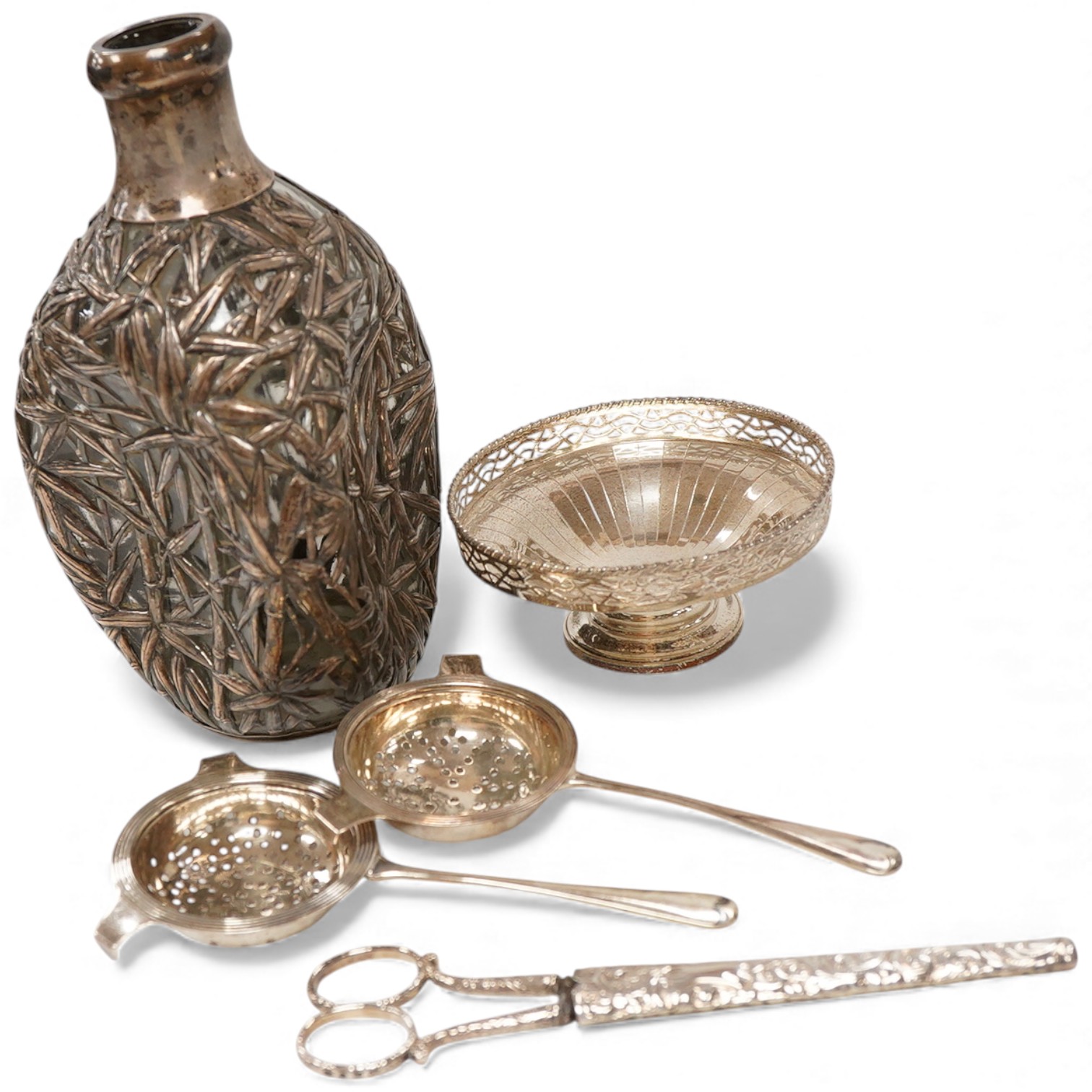 A Chinese sterling mounted dimpled glass decanter, with bamboo decoration, lacking stopper, approx. 19.5cm, together with a George V silver pedestal bonbon bowl, a pair of silver tea strainers by Roberts & Belk and a pai